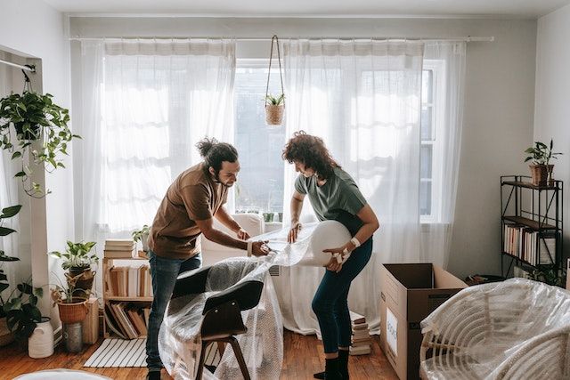 Two people prepare excess furniture for storage as part of the Do's and Don'ts of an open house for home sellers.