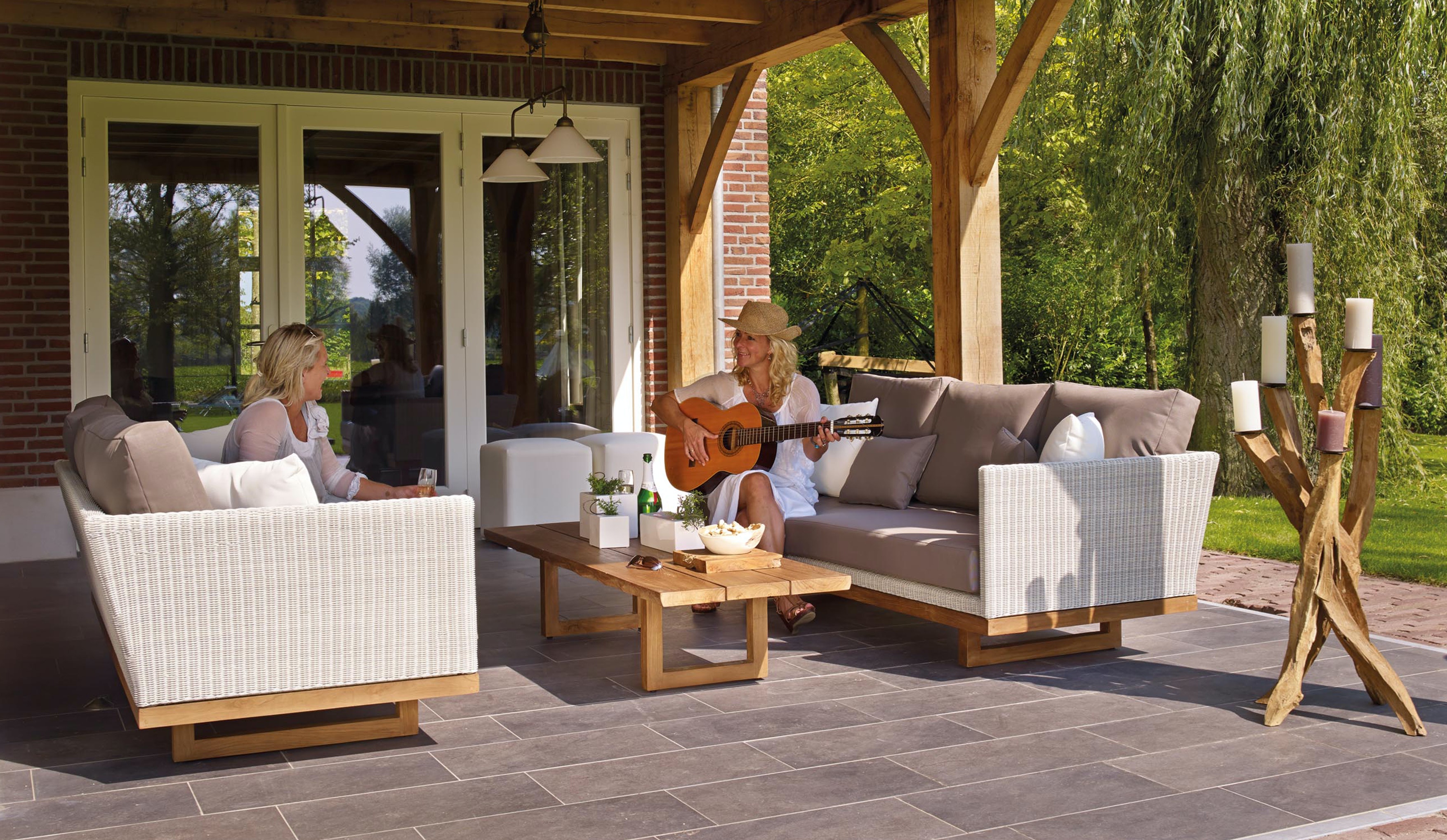 Two women sitting outside the home enjoying themselves, one is playing the guitar.