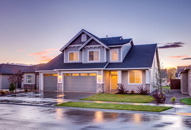 A blue and gray concrete house with an attic during twilight