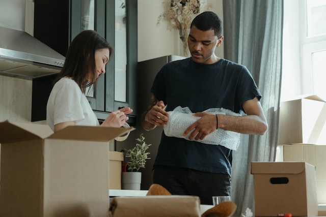 A man and a woman hold essential packing supplies, which are necessary for packing your home for a move.