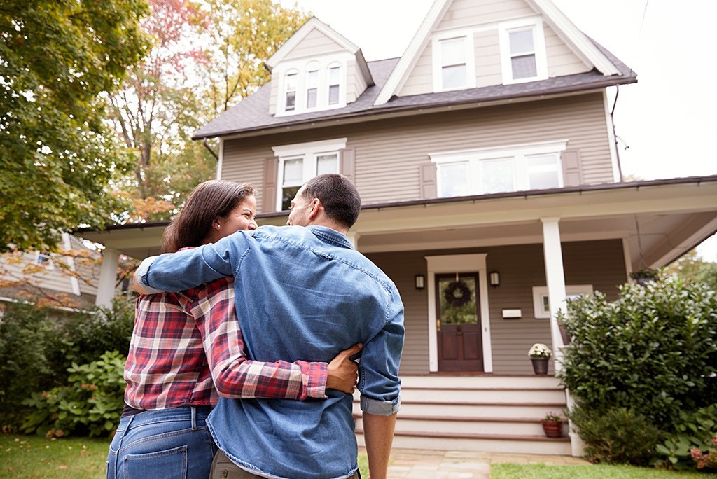 new homeowner couple in front of their new home