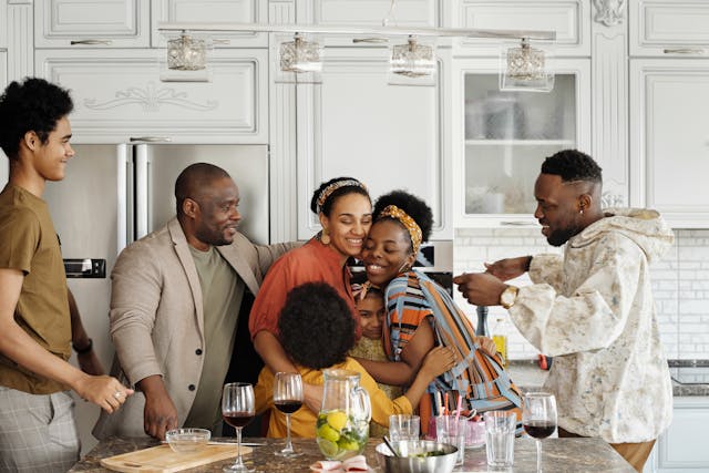 Family and friends gathered in a modern kitchen, sharing food and drinks