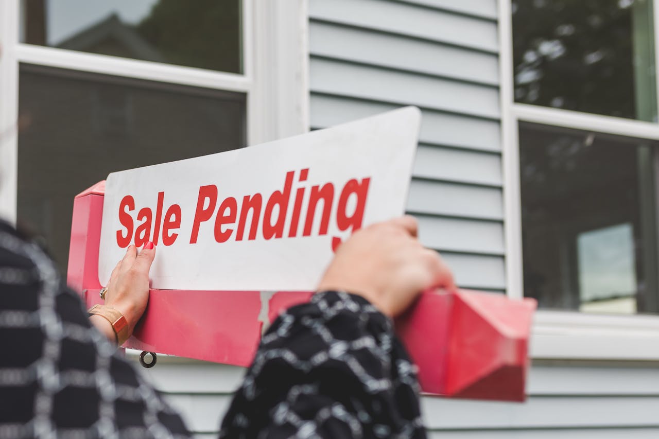 A person holding a sign outside of the house.