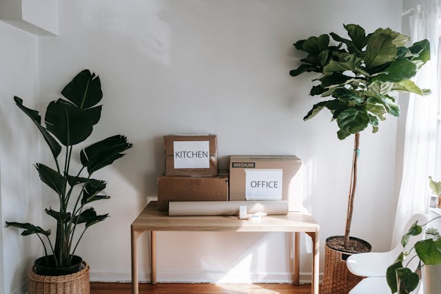 On a wooden table, a checklist for your moving day sits beside cardboard boxes ready for efficient packing