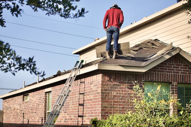 A man inspecting the roof of a house.