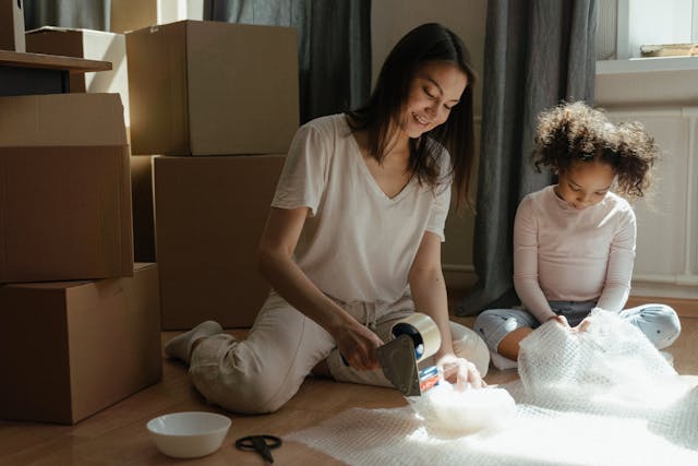 A woman and girl pack belongings together into boxes