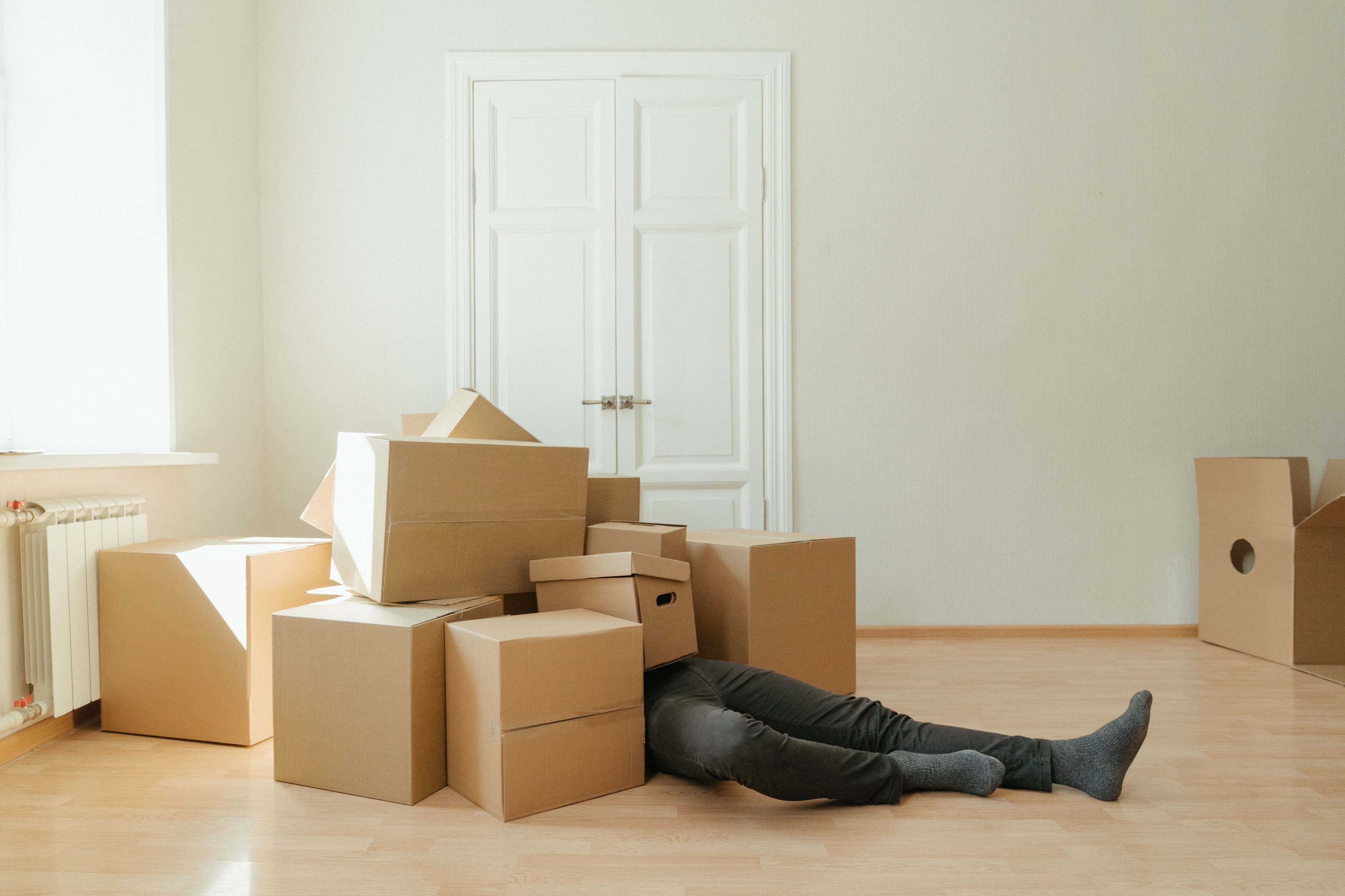 A person lying below many cardboard boxes.