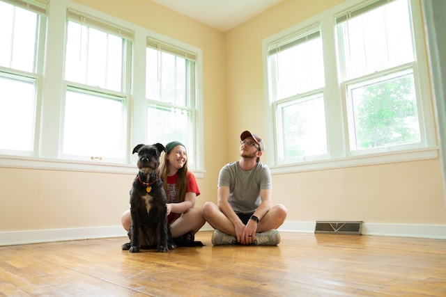 A couple with a dog sitting on the floor.